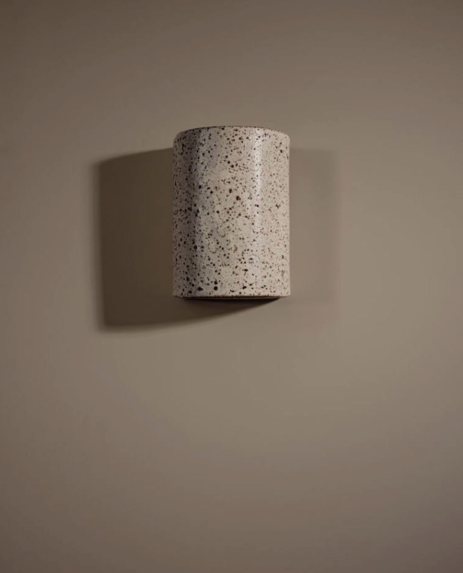 Cylindrical ceramic interior wall light on a brown background