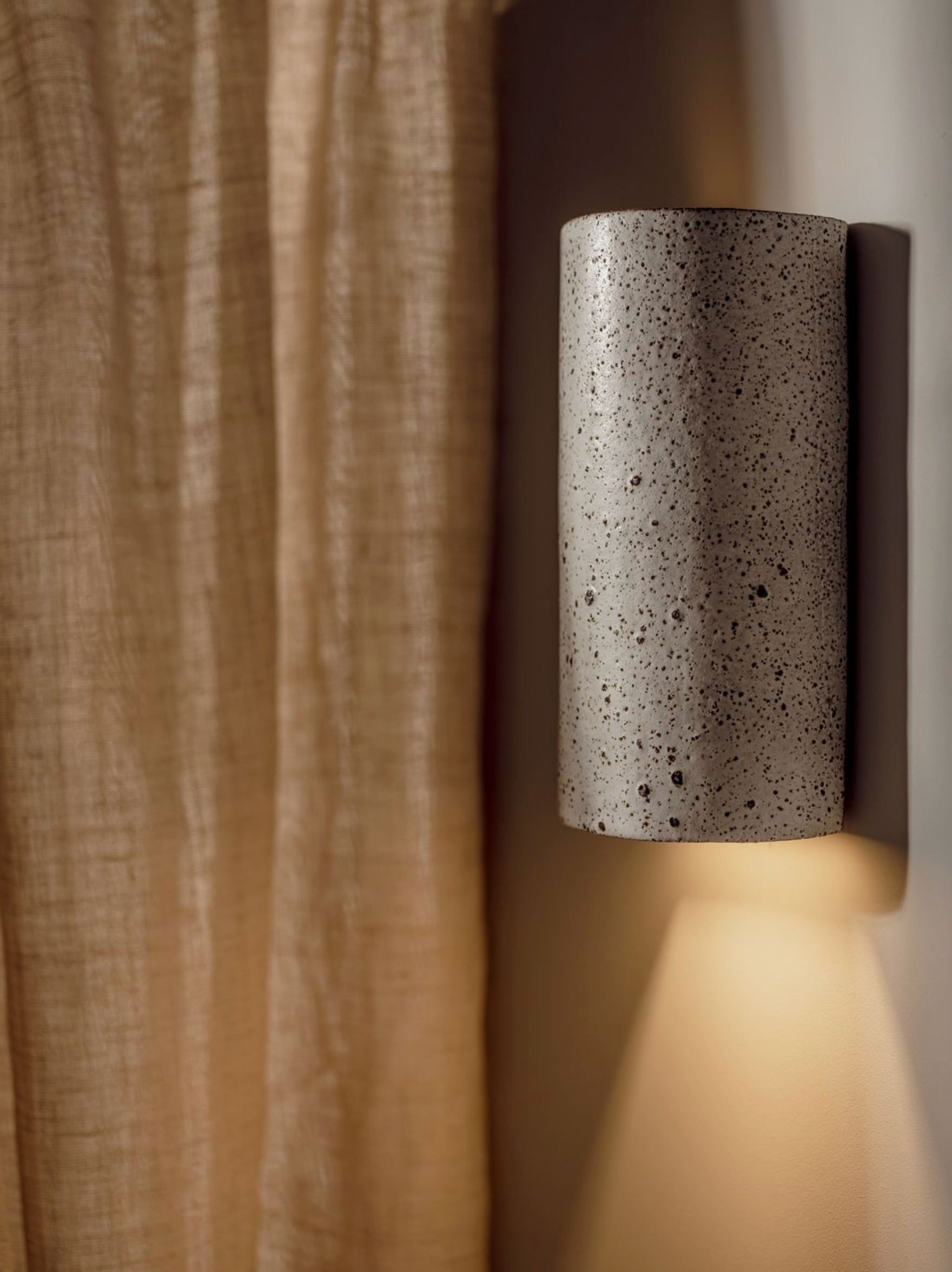 Cylindrical ceramic interior wall light fixture with textured surface background