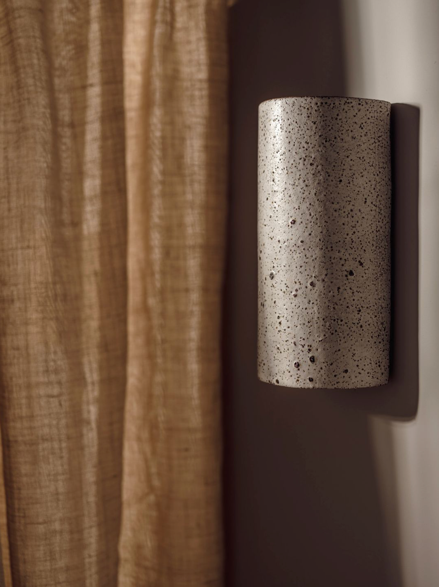 Cylindrical wall light fixture with textured surface on a neutral background