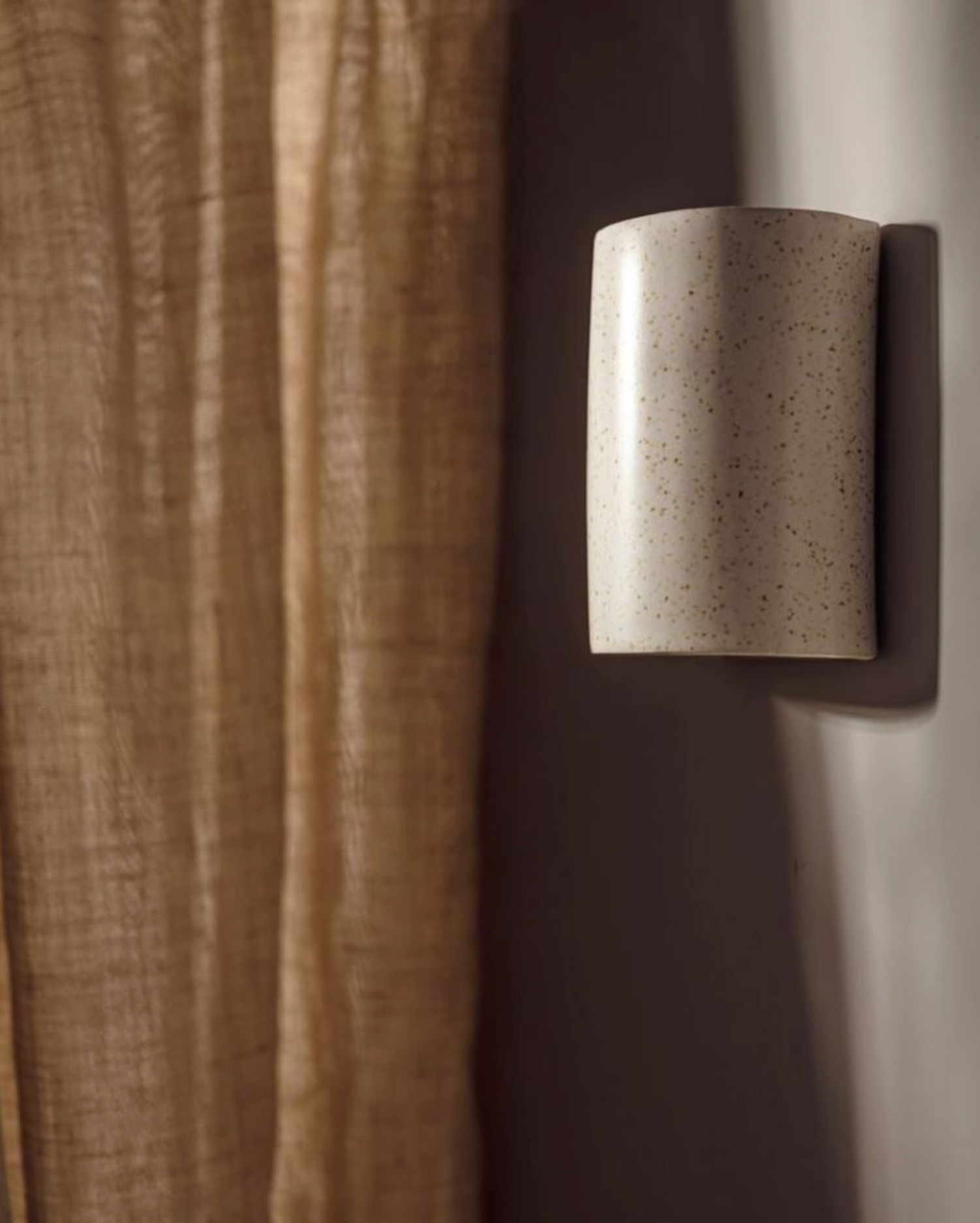 Cylindrical ceramic wall light fixture on a neutral background