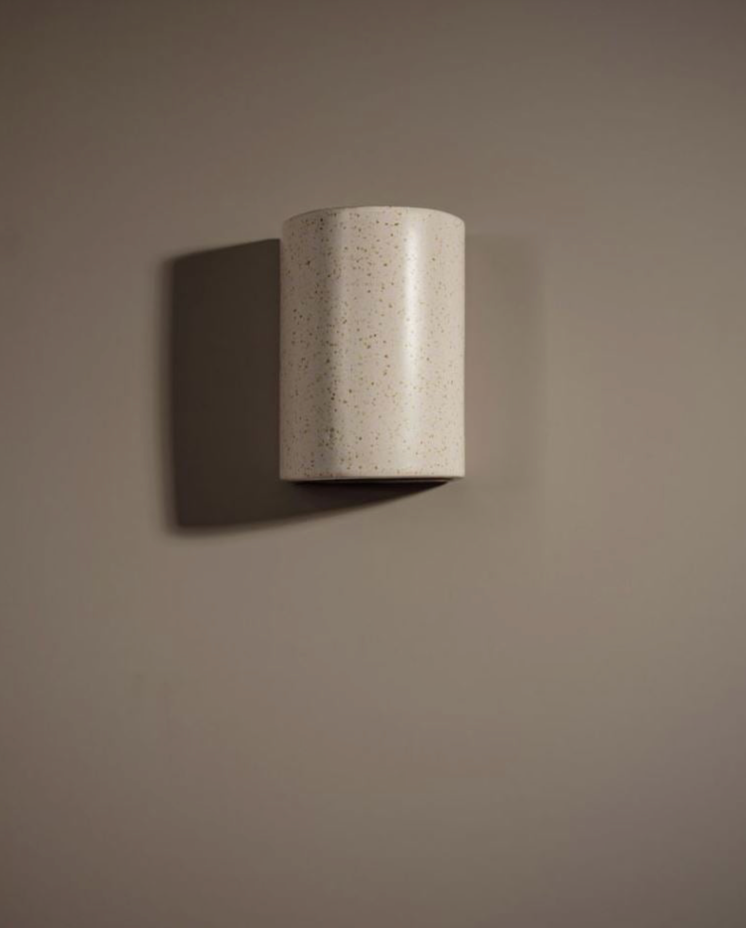Cylindrical ceramic textured wall light fixture on a plain wall