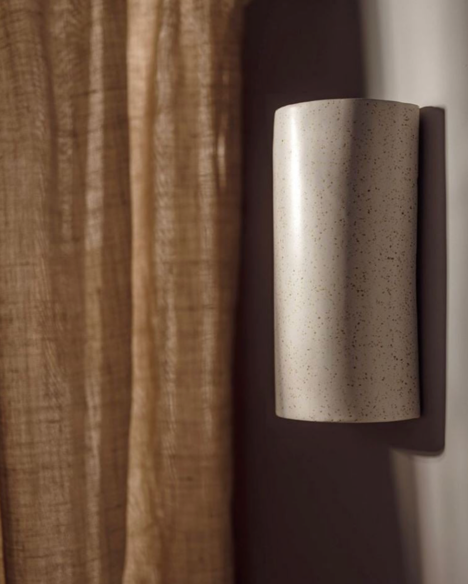 Cylindrical ceramic wall light fixture on a neutral background