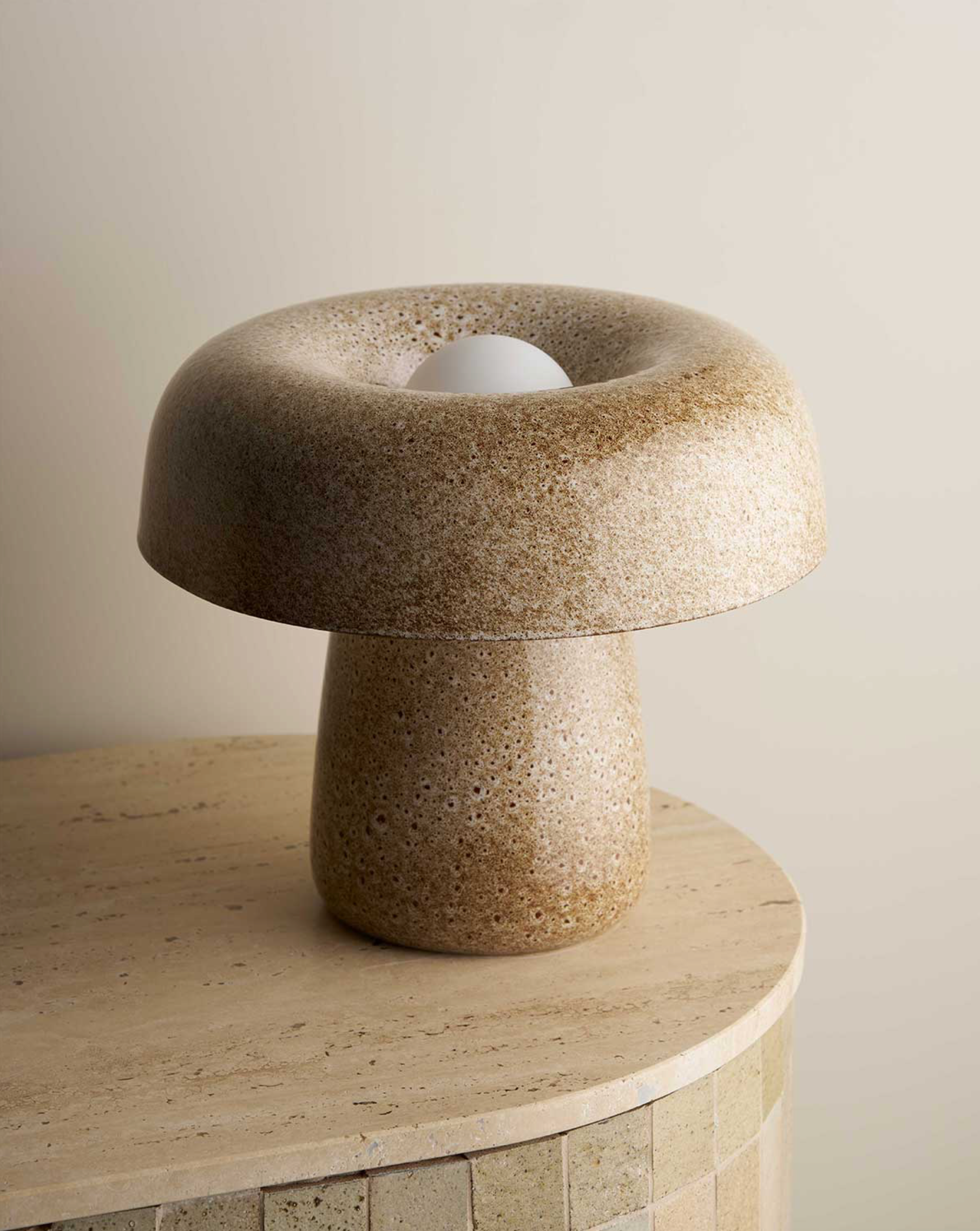Stylized stone ceramic lamp on a matching surface with a neutral background