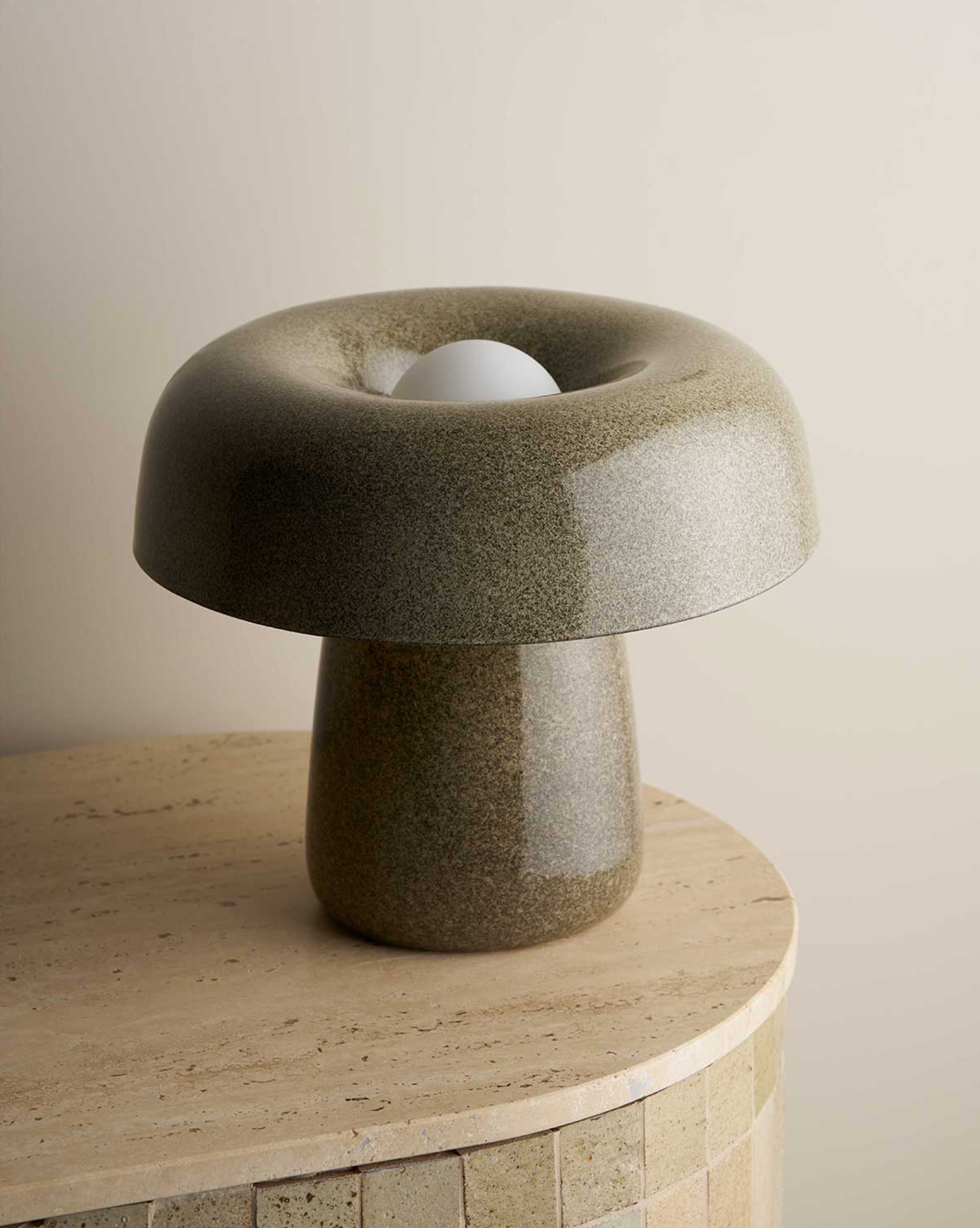 Modern stone-styled ceramic lamp on a wooden surface with a neutral background