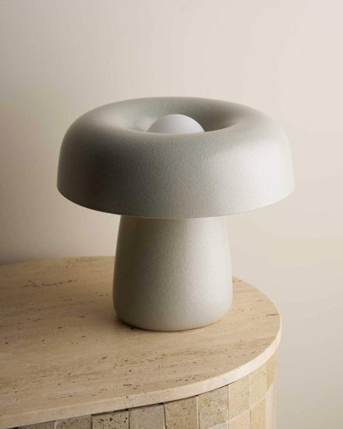 Grey textured mushroom-shaped lamp on a wooden surface with a neutral background
