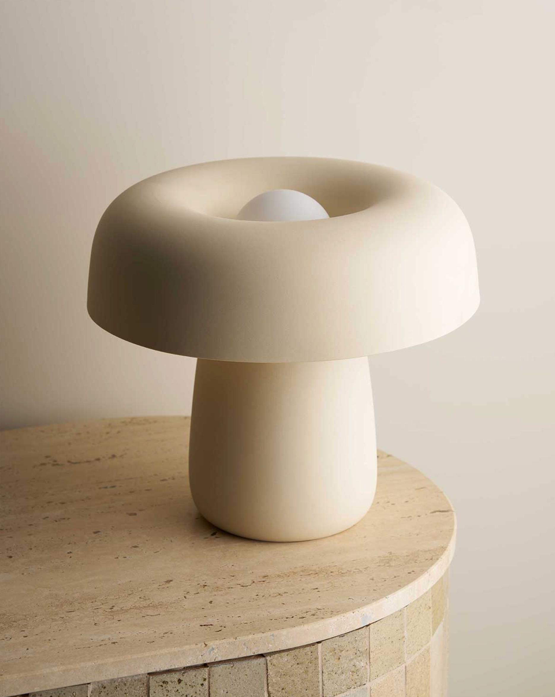 Beige mushroom-shaped lamp on a wooden surface with a neutral background