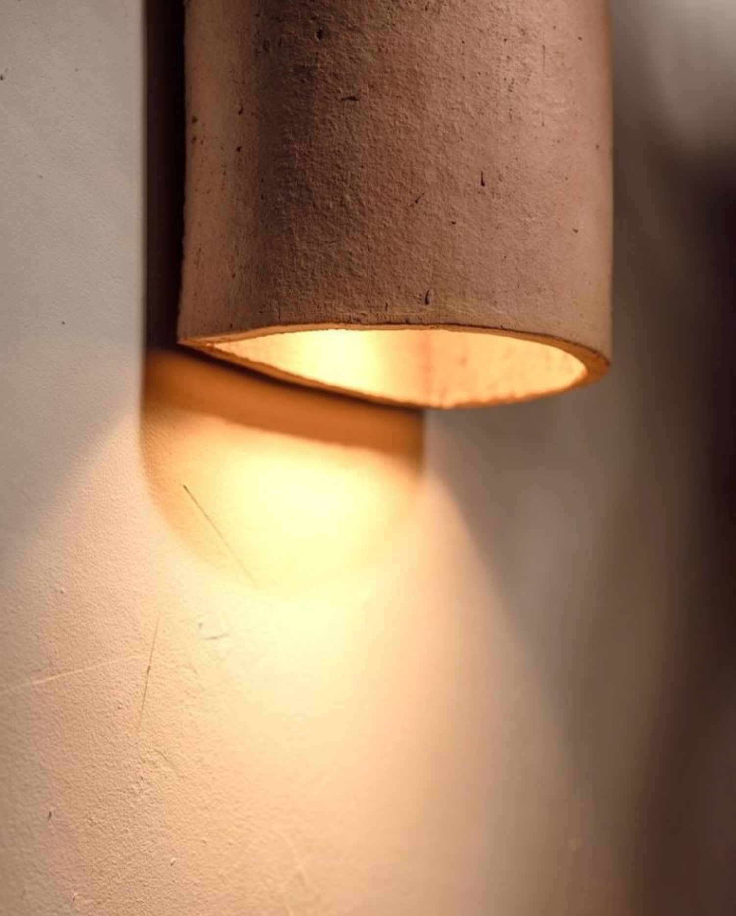 Nude terracotta cylindrical ceramic wall light fixture on a neutral background