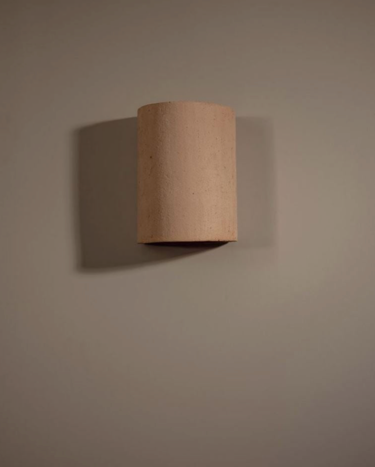 Cylindrical clay object on a beige wall