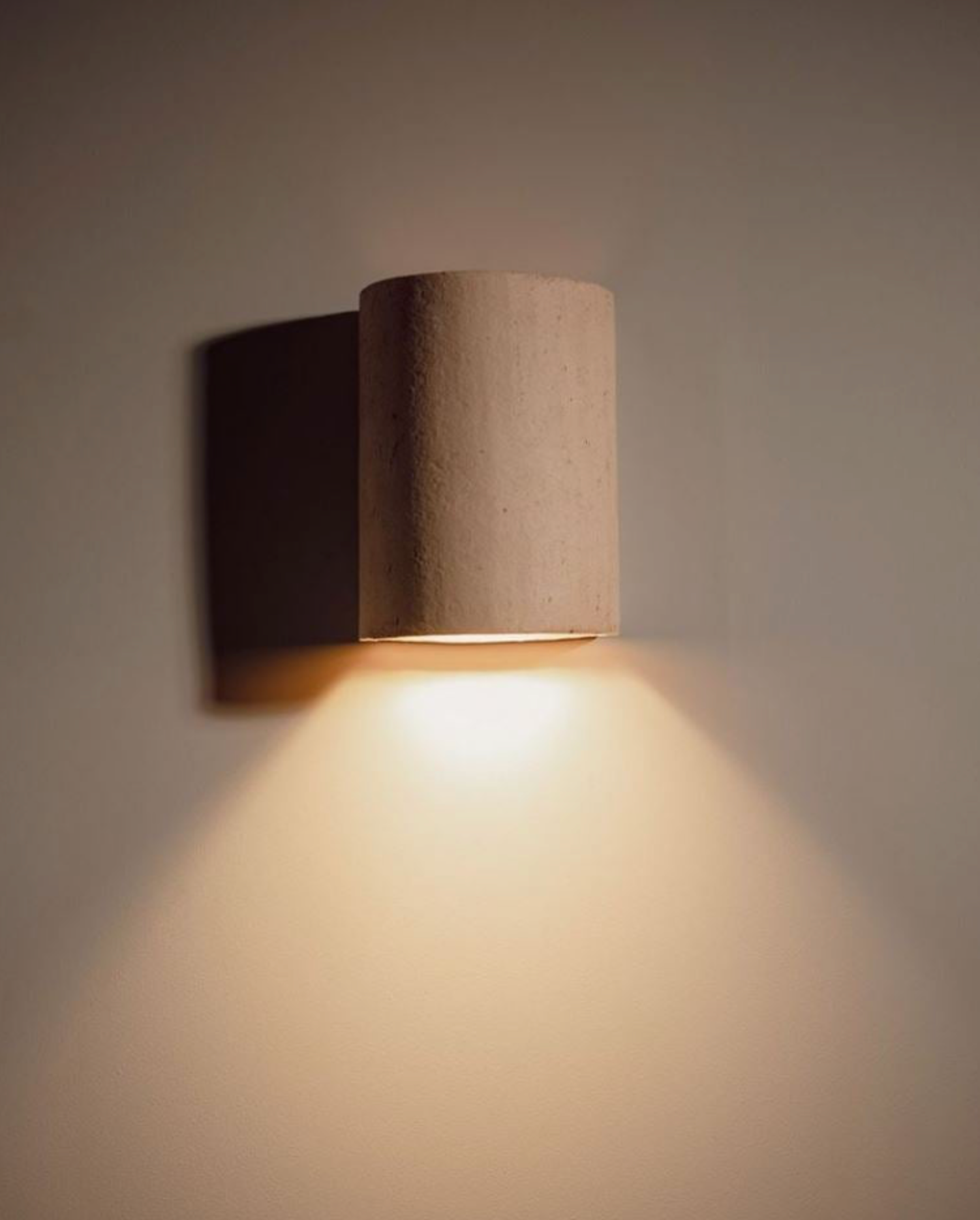 Cylindrical ceramic wall light fixture on a plain wall