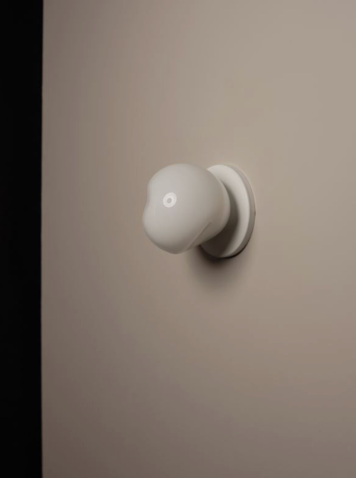 White mouth blown wall light on a beige wall