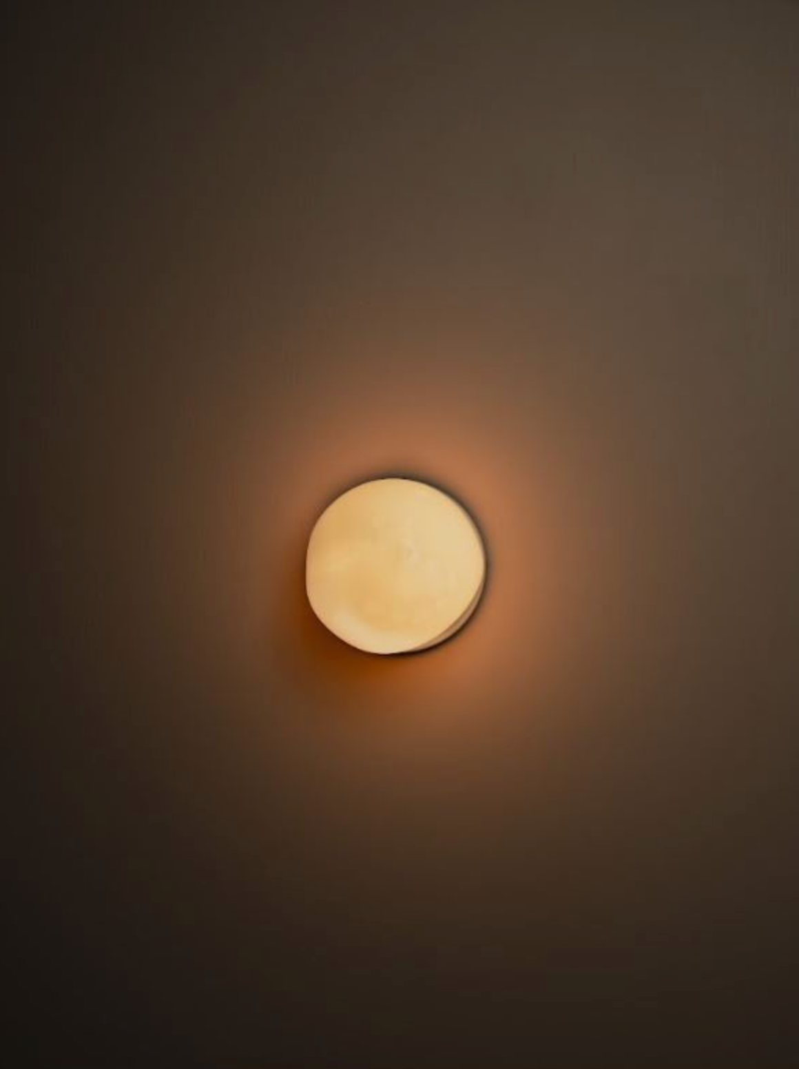 Round mouth blown wall light fixture on a dark wall