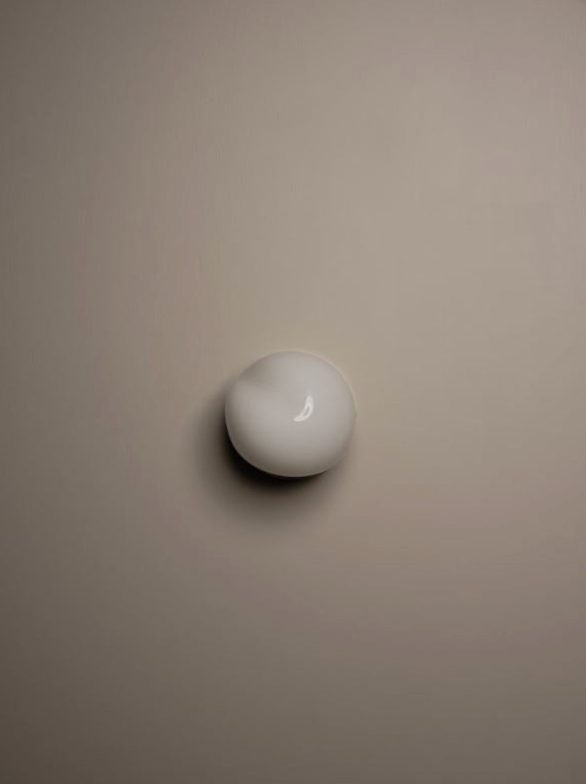 White glass wall sconce on a beige wall
