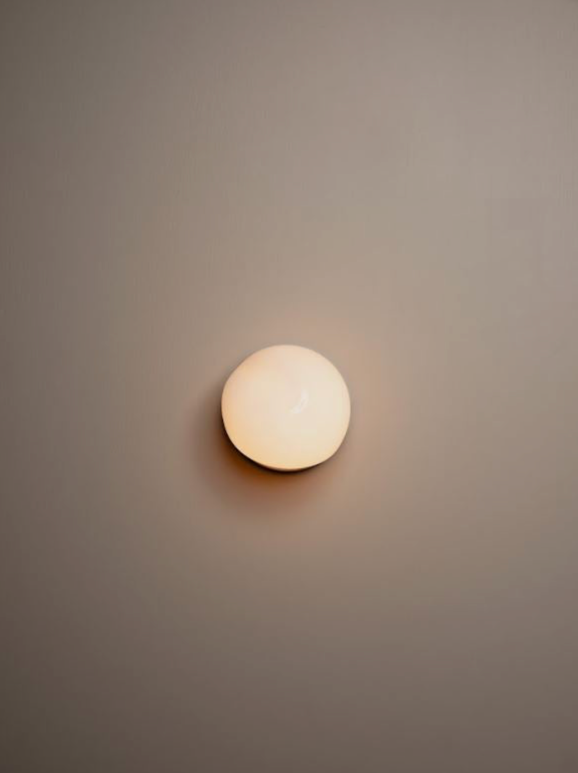 Round glass wall light fixture on a plain wall