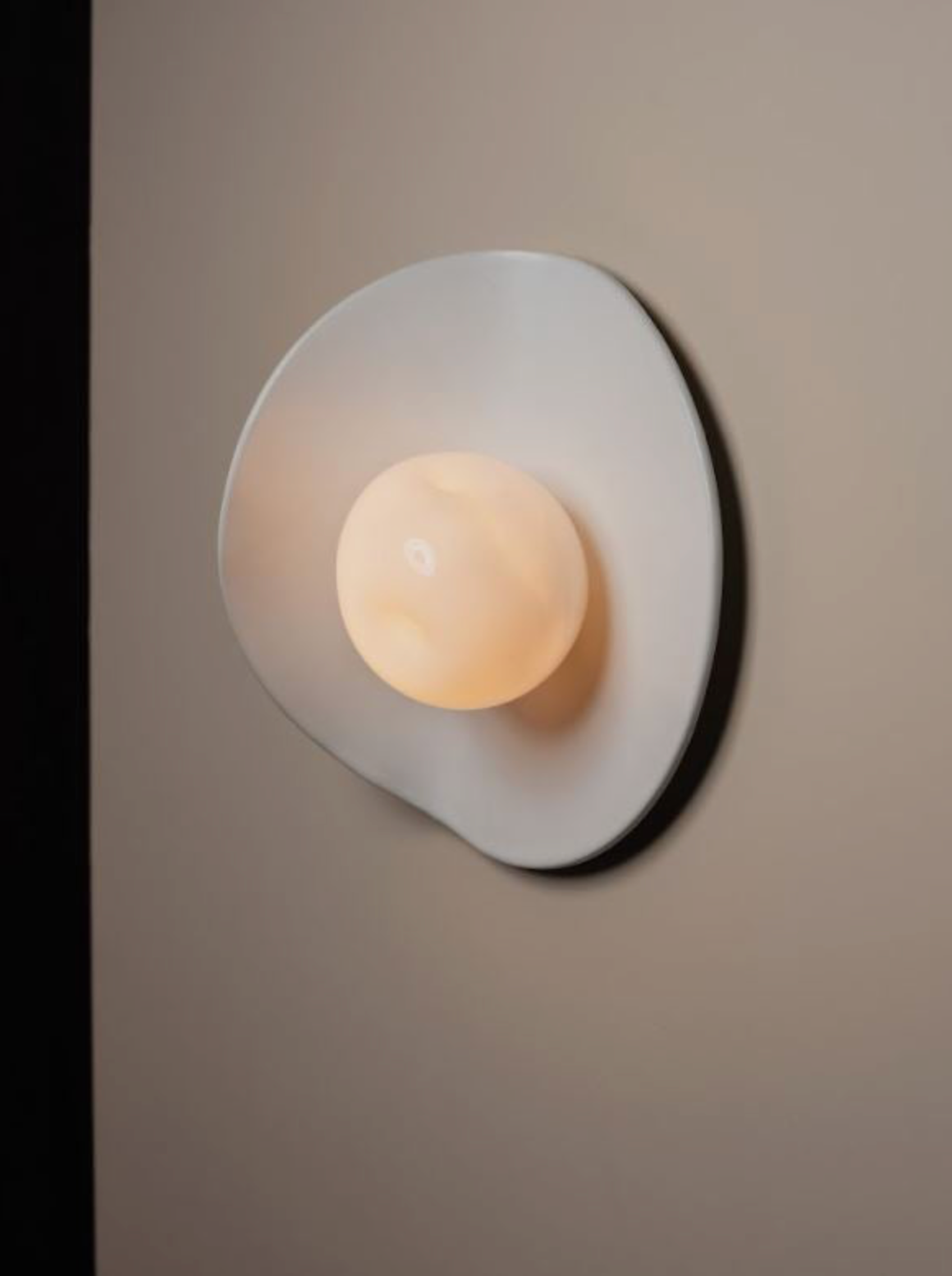 Wall-mounted light fixture with a soft glow on a neutral background