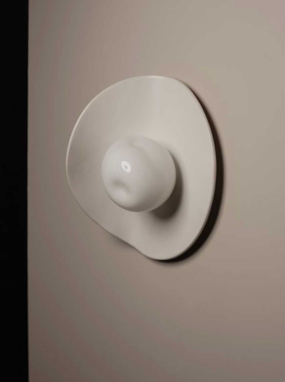 Handmade ceramic and glass wall light on a neutral wall