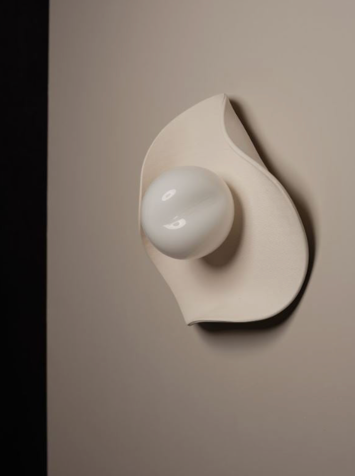 Hand made ceramic sconce fixture with a white mouth blown glass on a wall