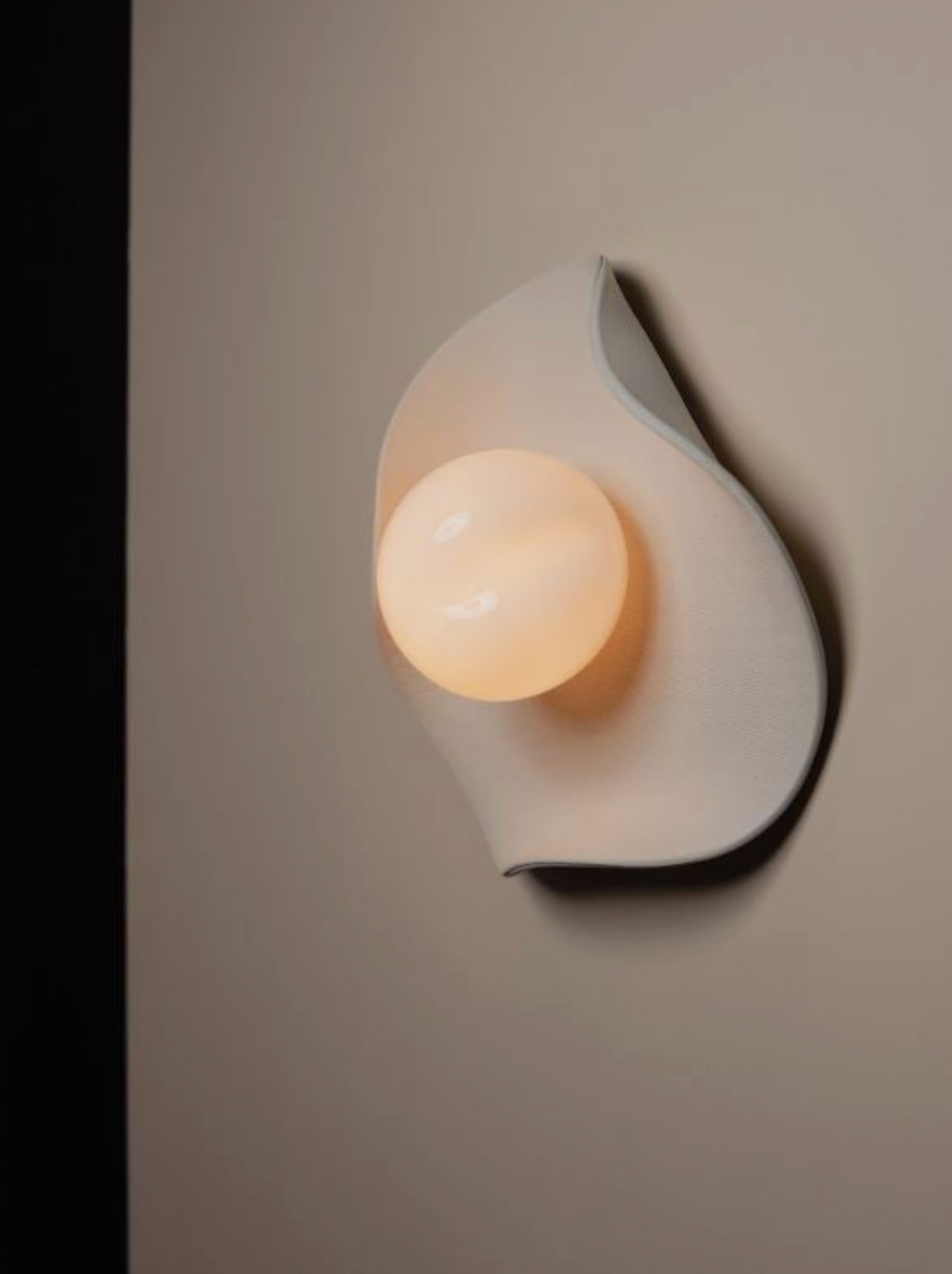 Modern hand made wall sconce with a warm light on a neutral background