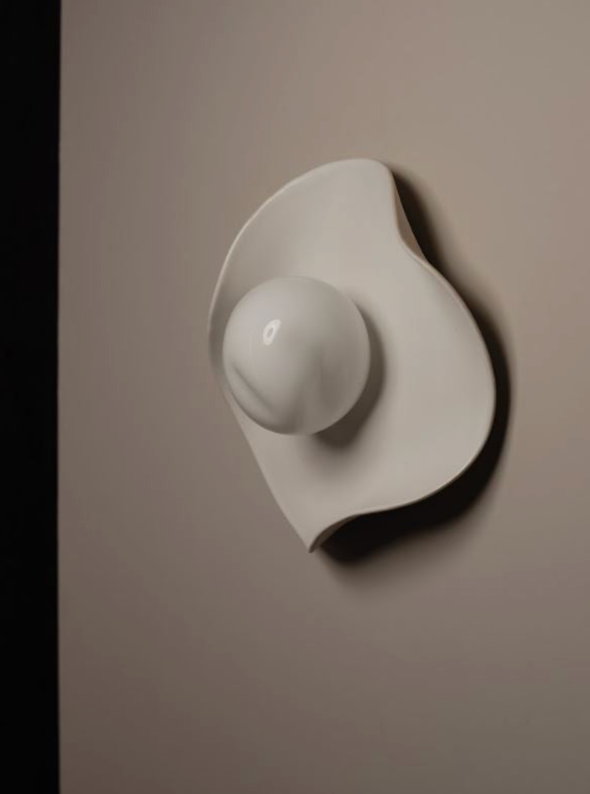 White ceramic wall sconce on a white wall