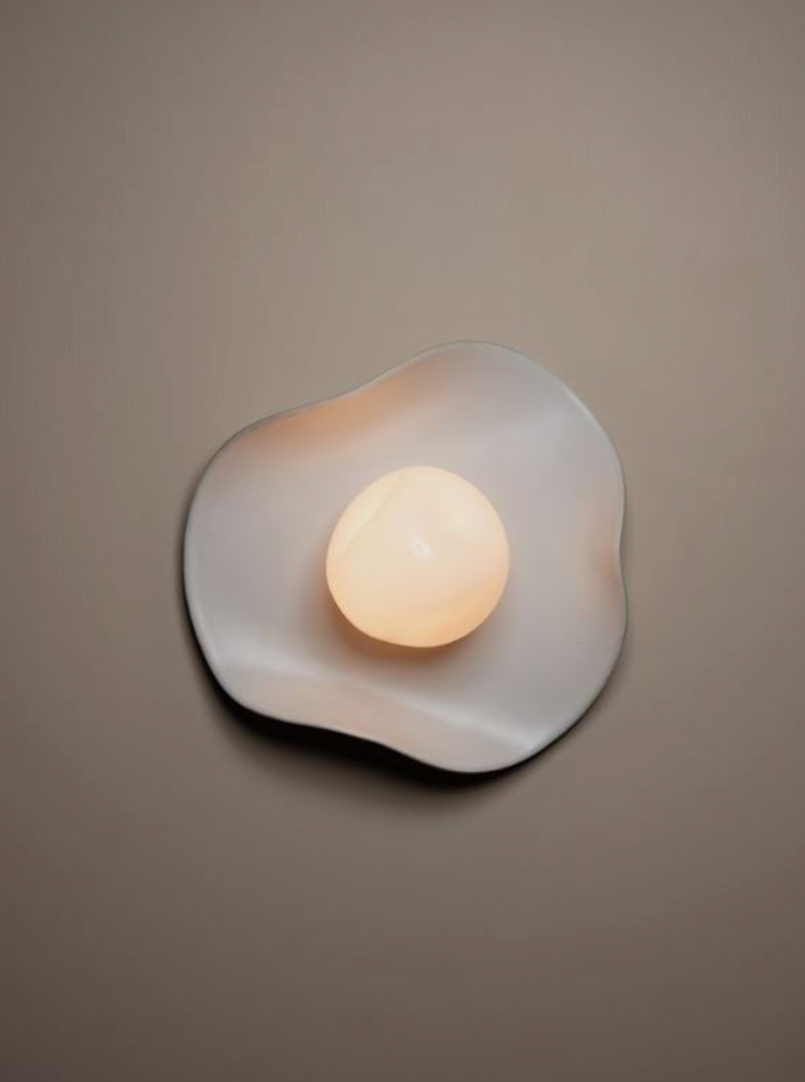 Wall-mounted light fixture with a soft warm glow on a neutral background