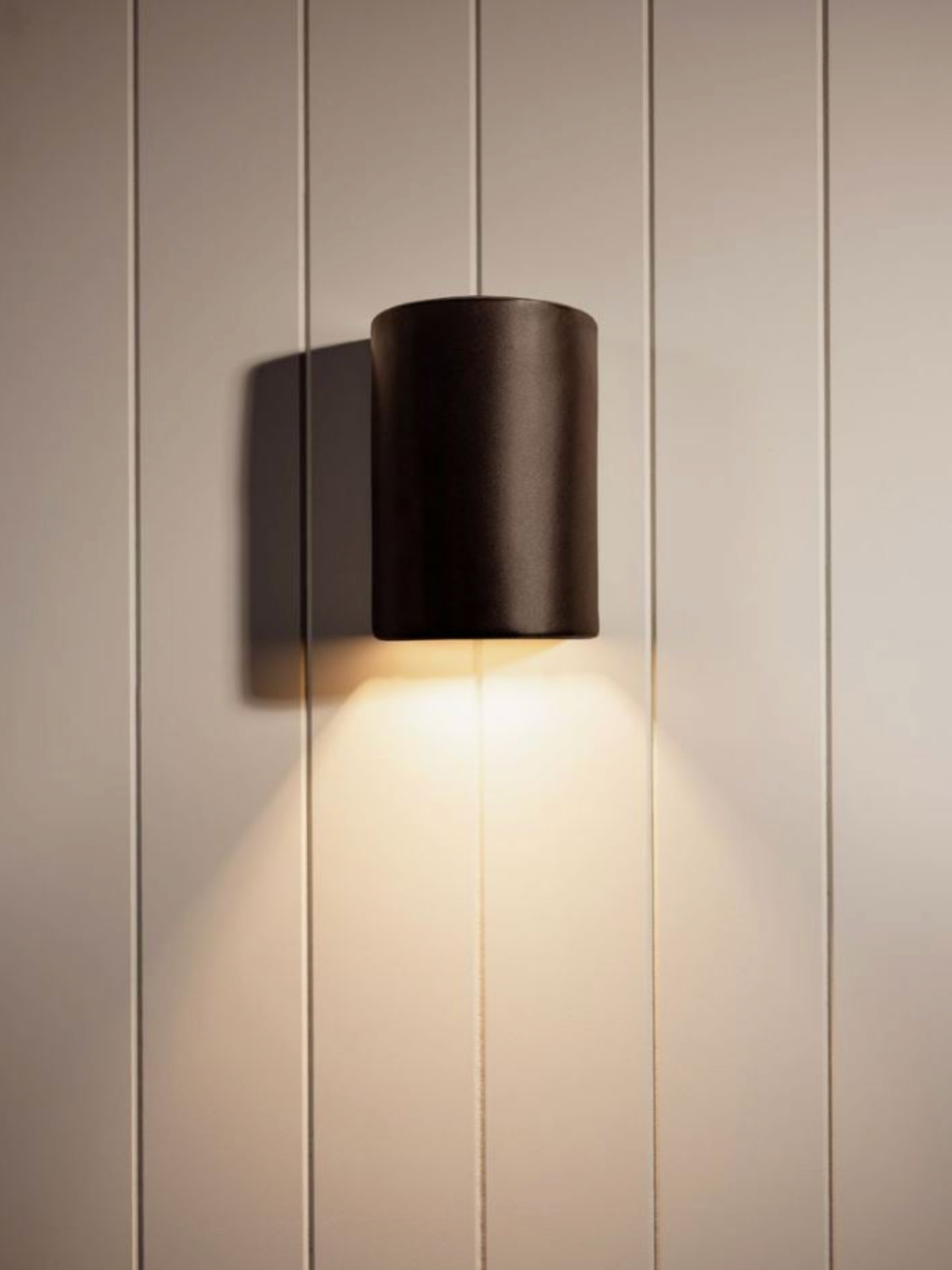 Modern hand made wall-mounted ceramic light fixture on a neutral wall