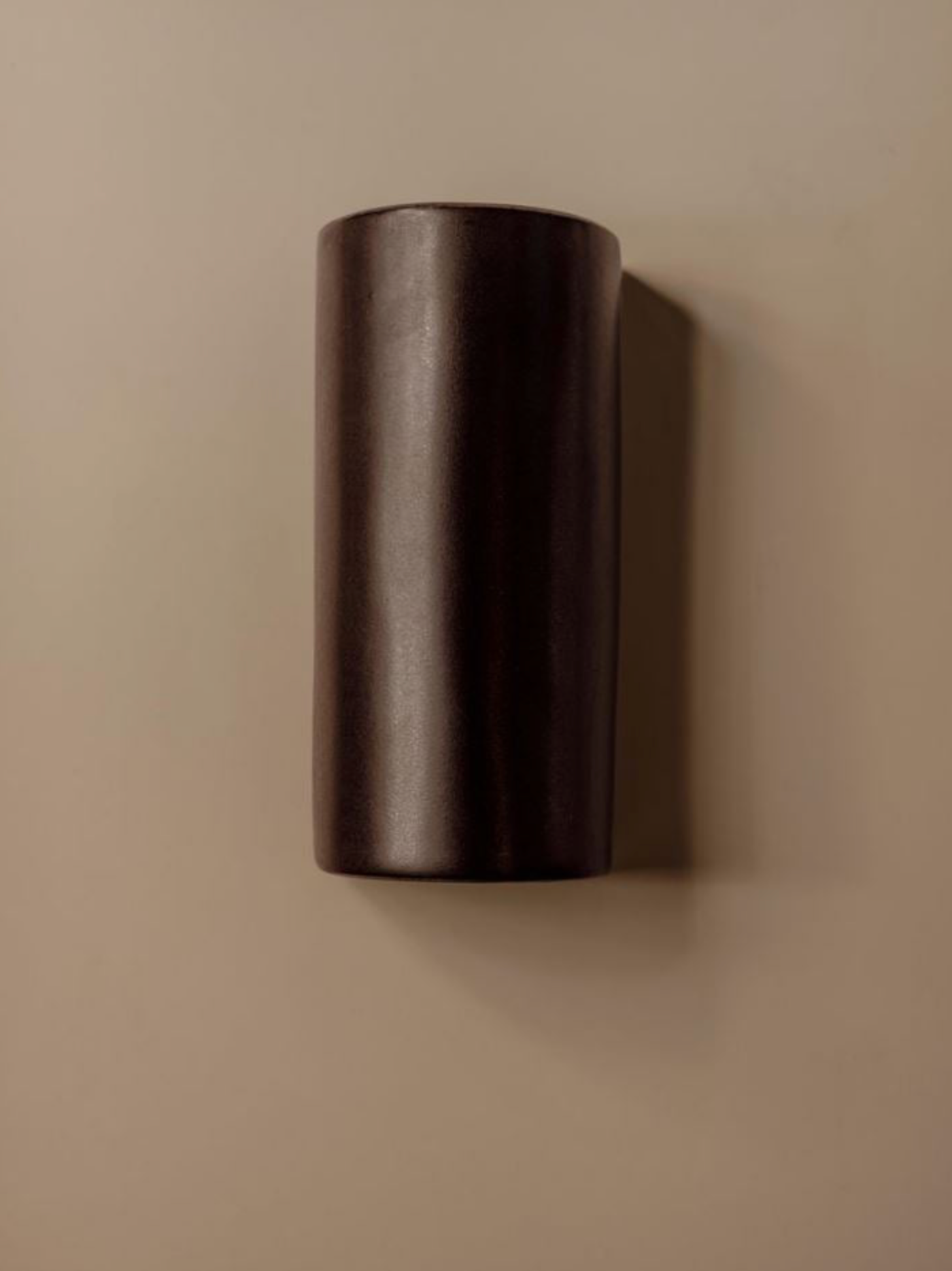 Dark cylindrical wall light on a beige background