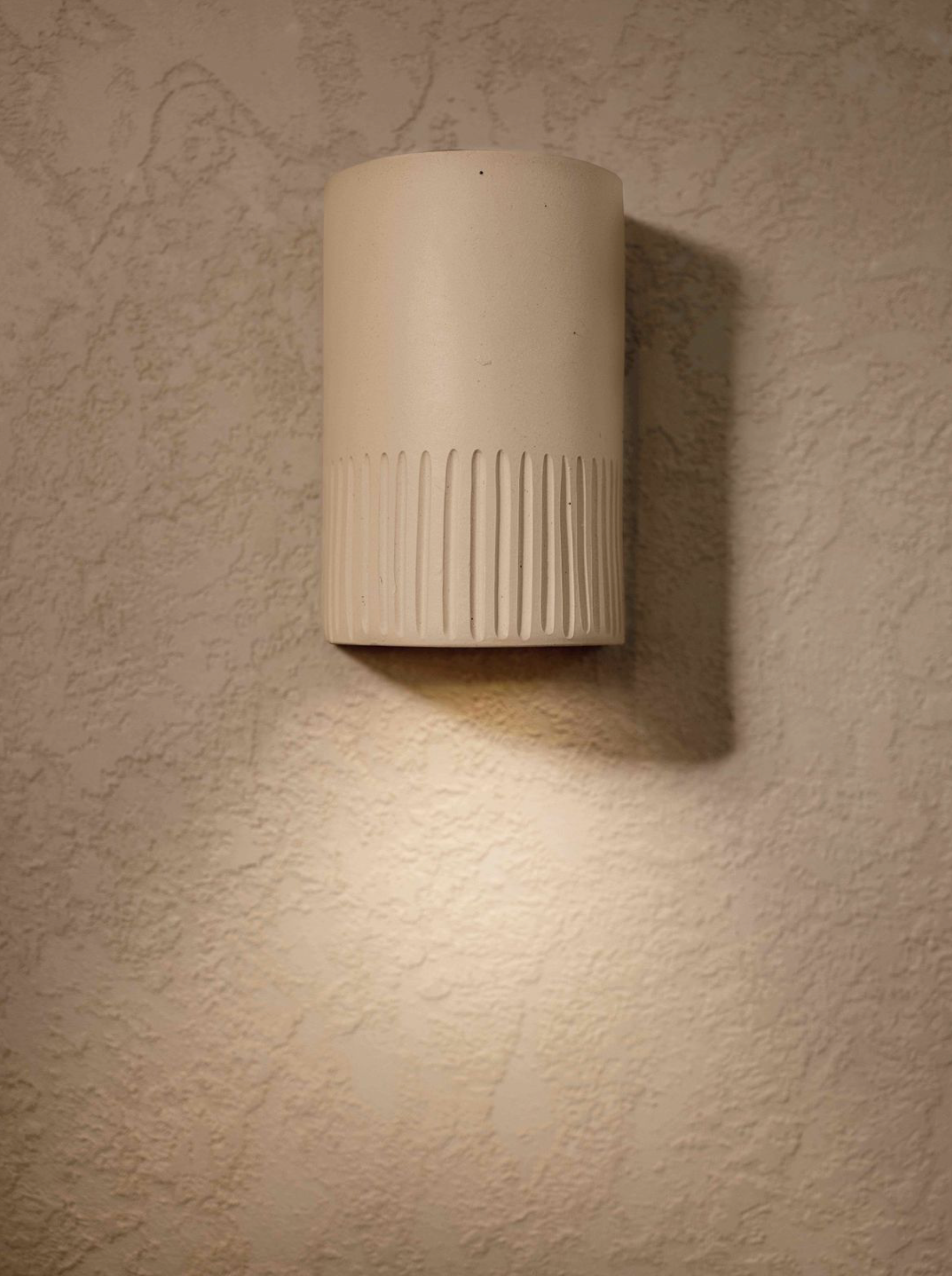 Clay handmade beige wall sconce on a textured wall