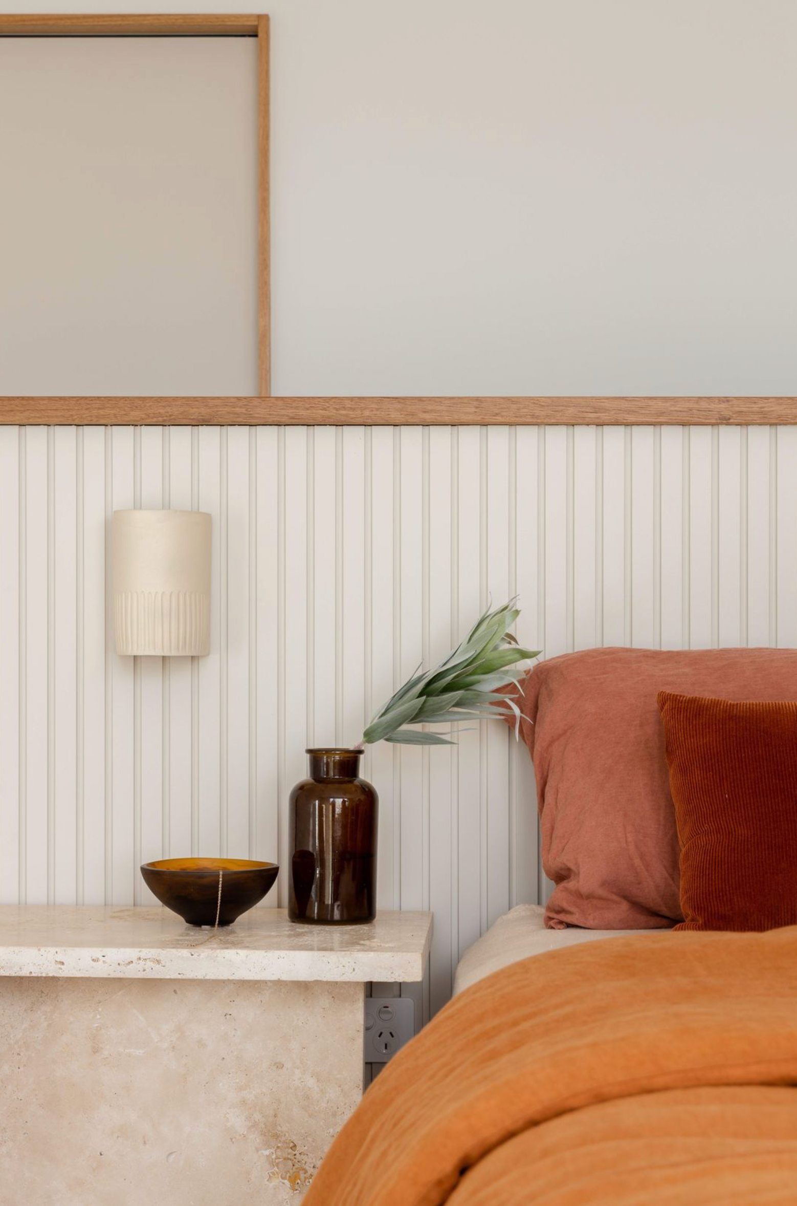 Bedroom with a bedside wall sconce, nightstand, lamp, and decorative items.