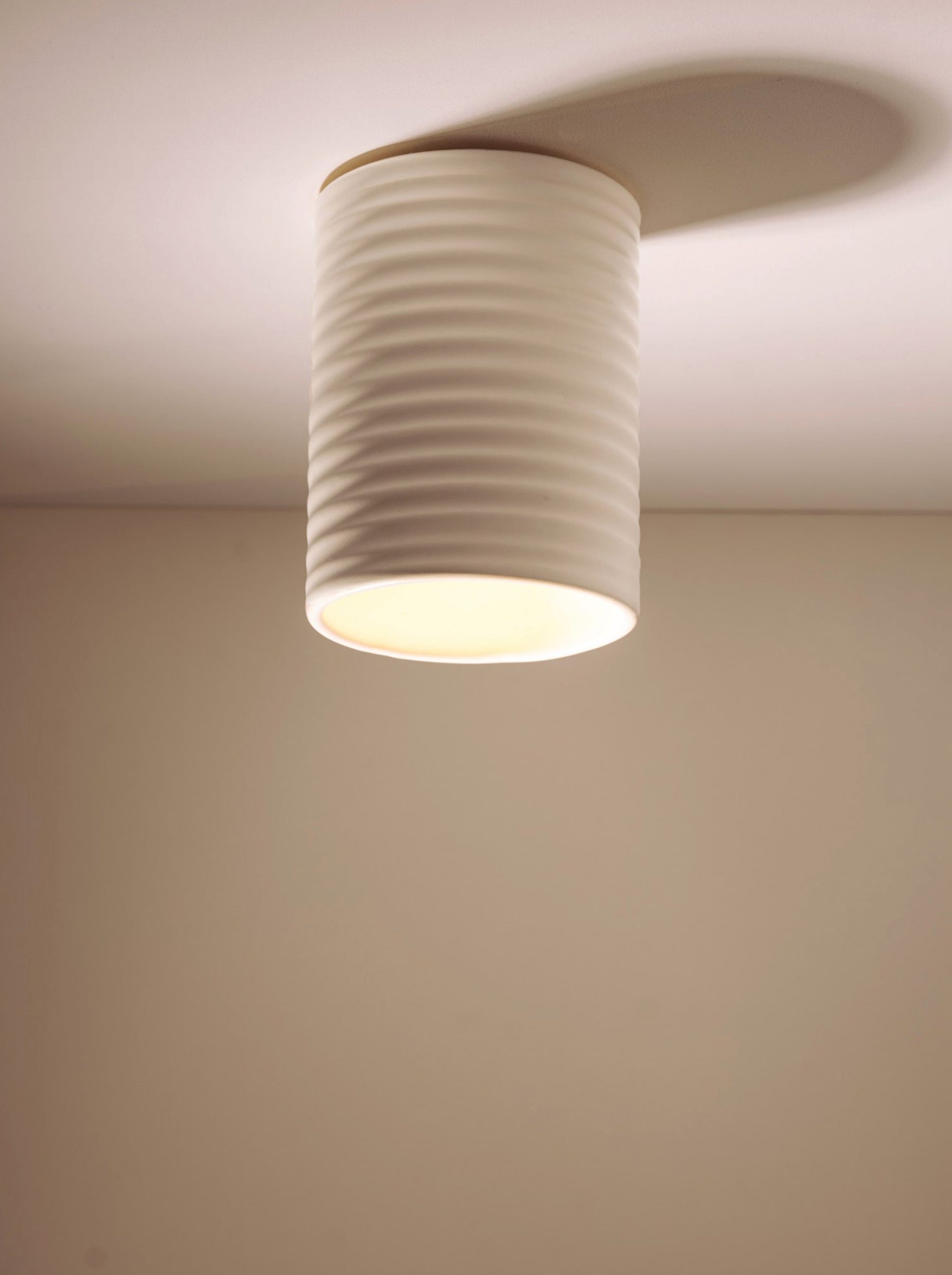Ceiling light fixture with textured white design on a plain wall.