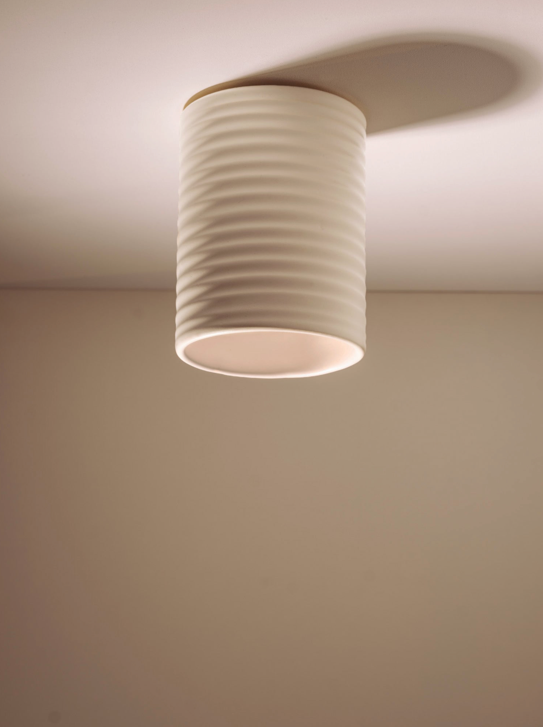 Ceiling light fixture with ribbed design on a plain wall.