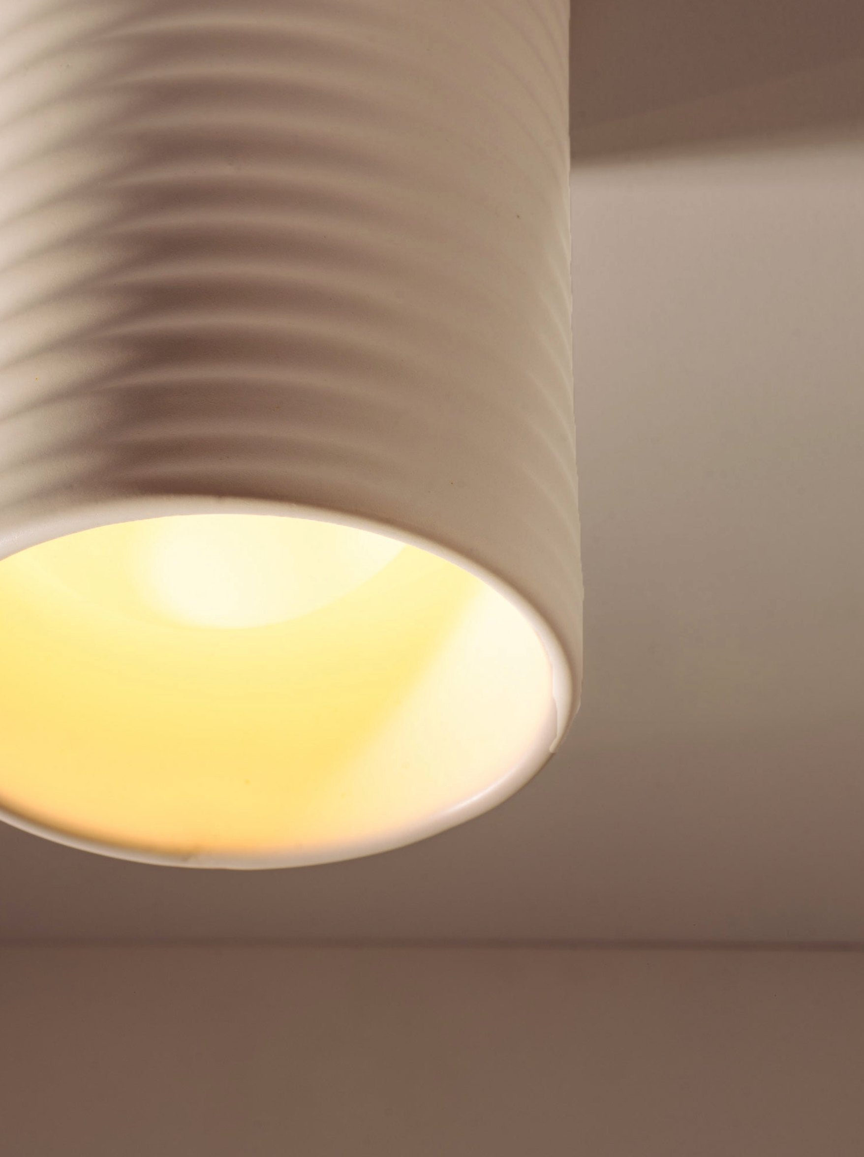 Close-up of a ceiling light fixture with a soft glow on a neutral background