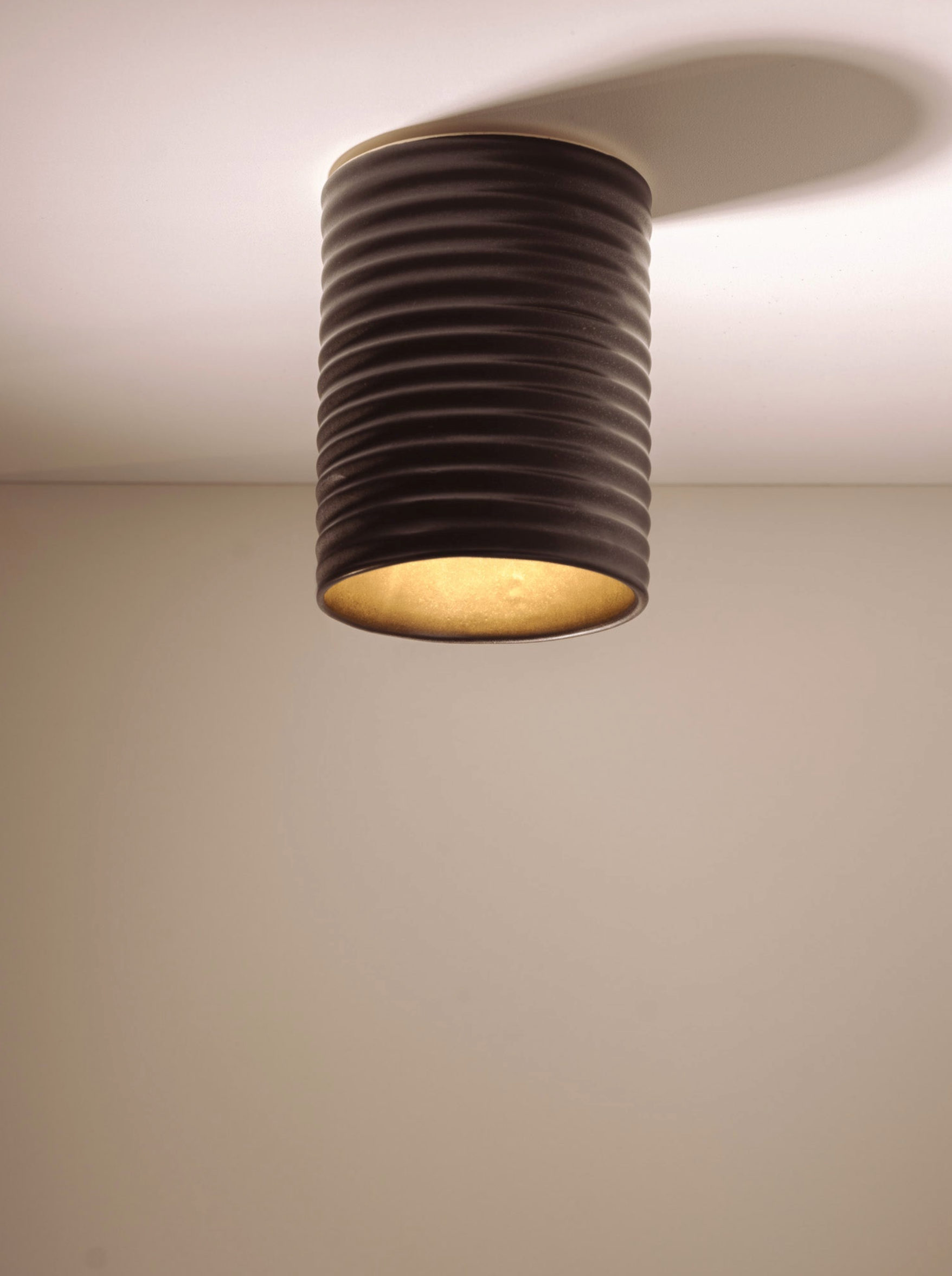 Ceiling light fixture with ribbed design on a plain ceiling. 