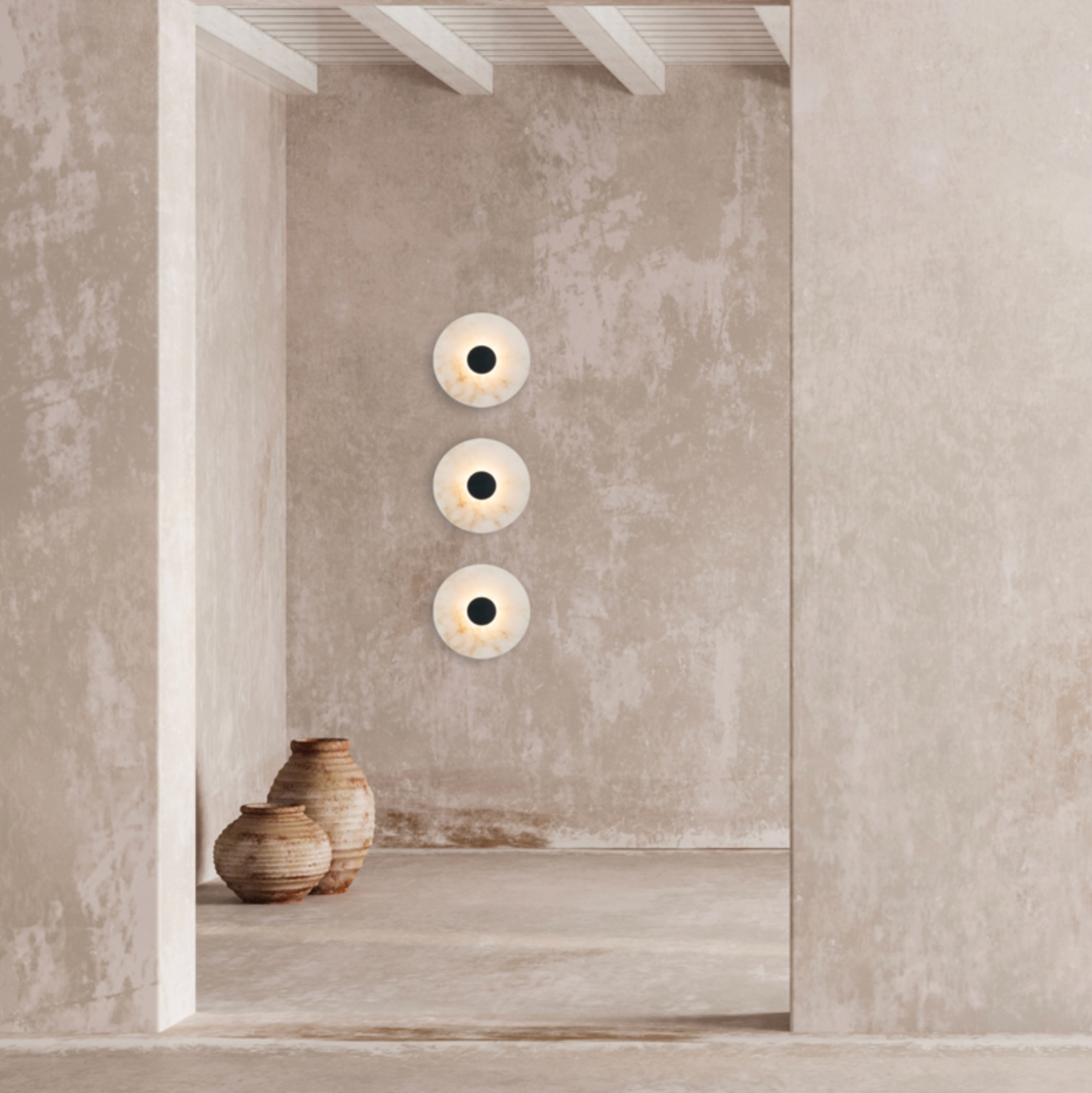 Three wall-mounted circular lights on a textured wall with two ceramic vases below.