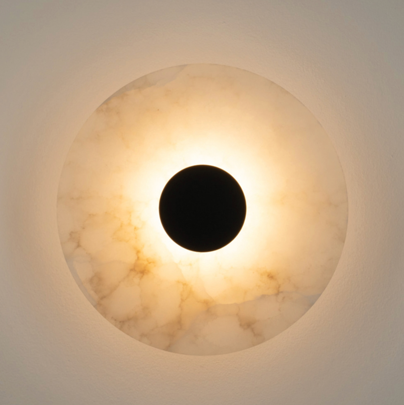 Round wall light fixture with marble-like texture on a neutral background