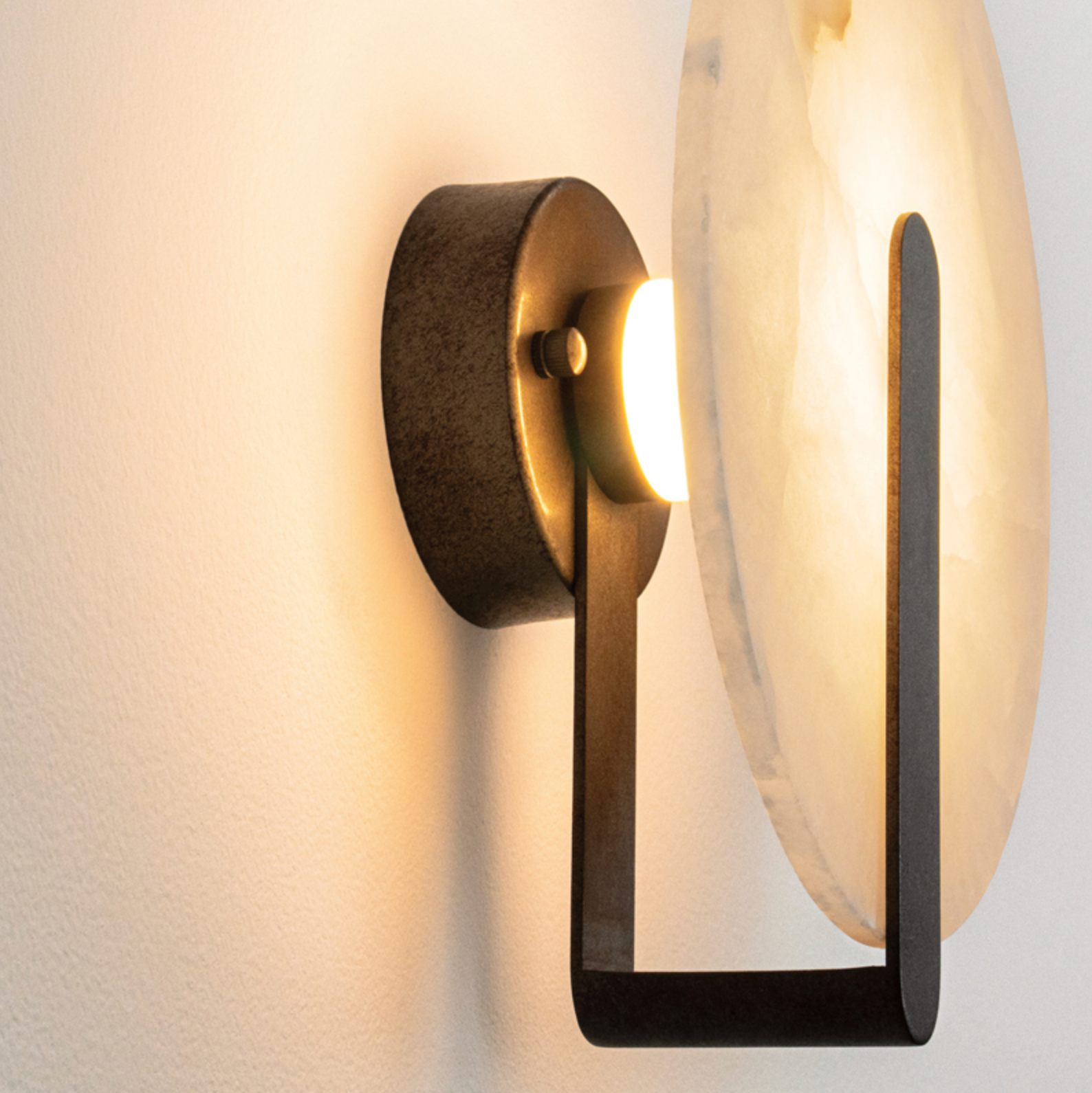 Modern wall light fixture with a warm glow on a neutral background