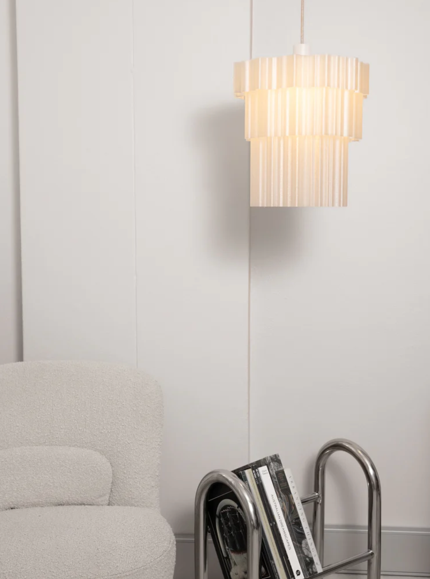 Delphine Pendant Light Pearl three-tiered 3D printed shade illuminated hanging above grey armchair – Franca Studio